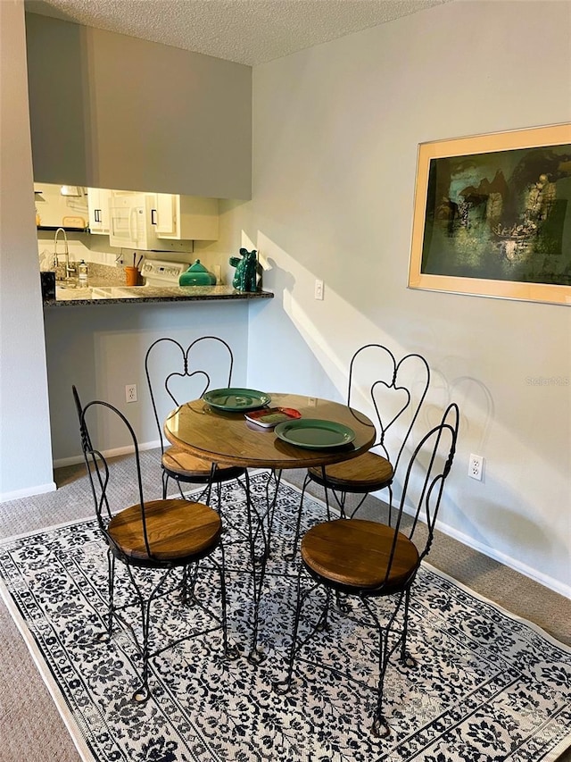 dining area with carpet floors, baseboards, and a textured ceiling