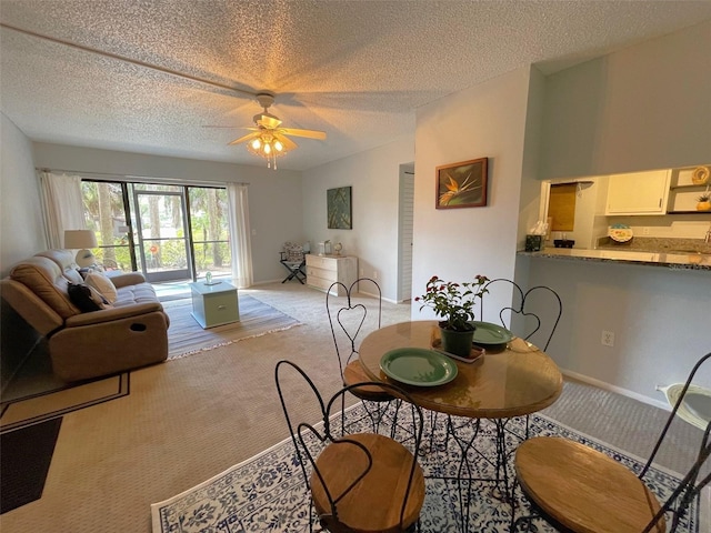 dining room with light carpet, ceiling fan, baseboards, and a textured ceiling