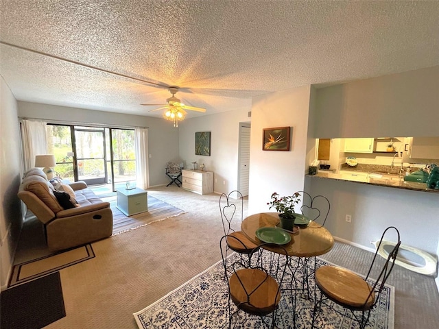 carpeted dining space with a textured ceiling, baseboards, and a ceiling fan