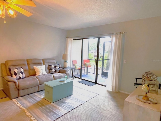 living room featuring a ceiling fan, light carpet, a textured ceiling, and baseboards