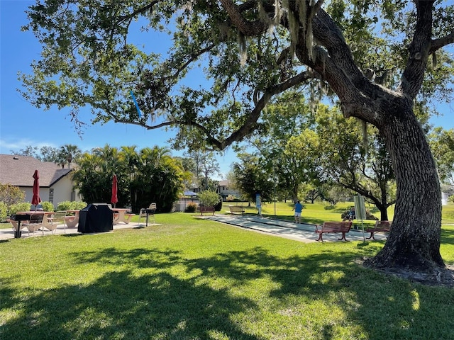 view of property's community featuring a yard and shuffleboard