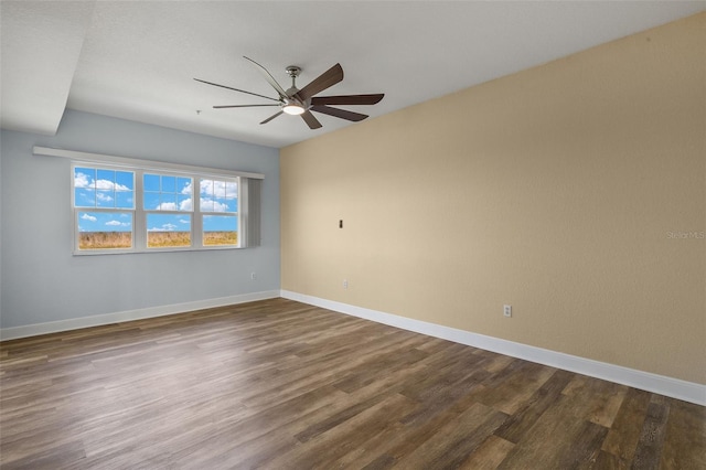 spare room with baseboards, dark wood finished floors, and a ceiling fan