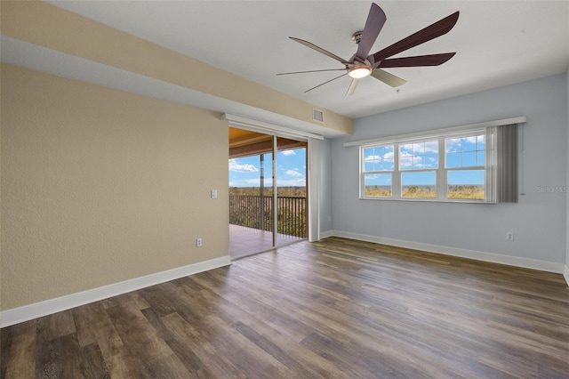empty room with baseboards, visible vents, dark wood-style flooring, and ceiling fan
