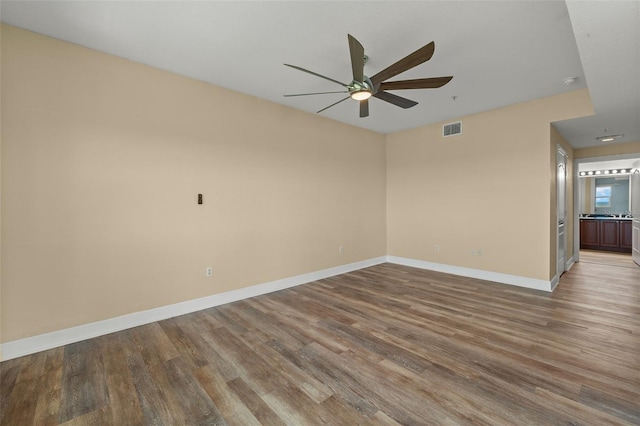 empty room featuring baseboards, wood finished floors, visible vents, and ceiling fan