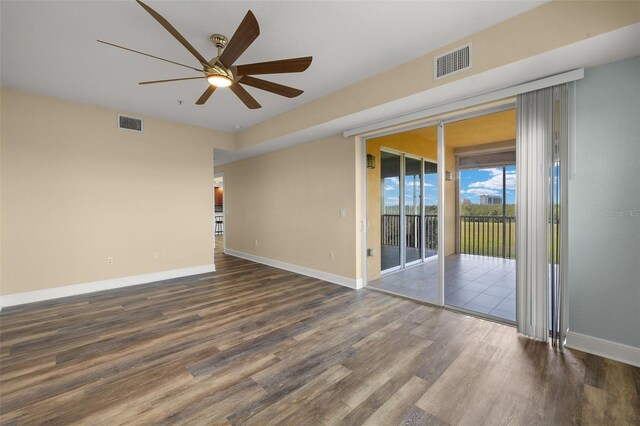 empty room featuring wood finished floors, a ceiling fan, visible vents, and baseboards