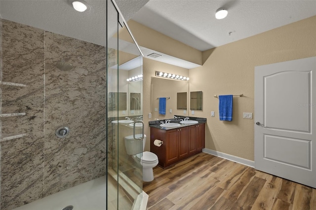 bathroom with double vanity, wood finished floors, a stall shower, and a sink