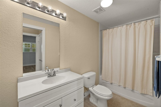 full bathroom with visible vents, toilet, vanity, and a textured wall