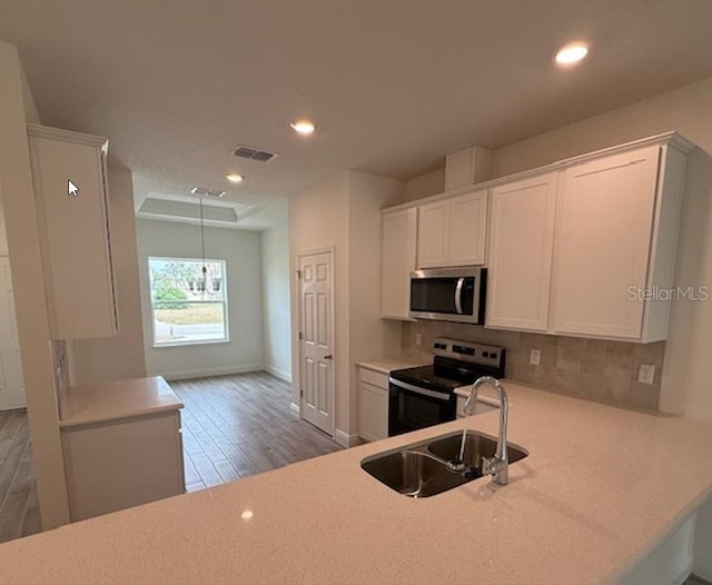 kitchen with sink, range with electric stovetop, kitchen peninsula, decorative backsplash, and white cabinets