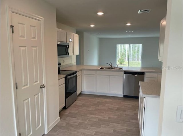 363 Underwood Trl, Palm Coast, FL 32164 - kitchen with a sink, a peninsula, appliances with stainless steel finishes, white cabinets, and light countertops