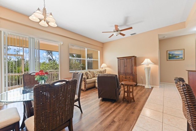 dining area with ceiling fan with notable chandelier and light wood-type flooring