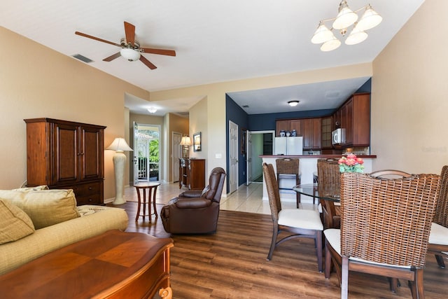 living room with ceiling fan with notable chandelier and wood-type flooring