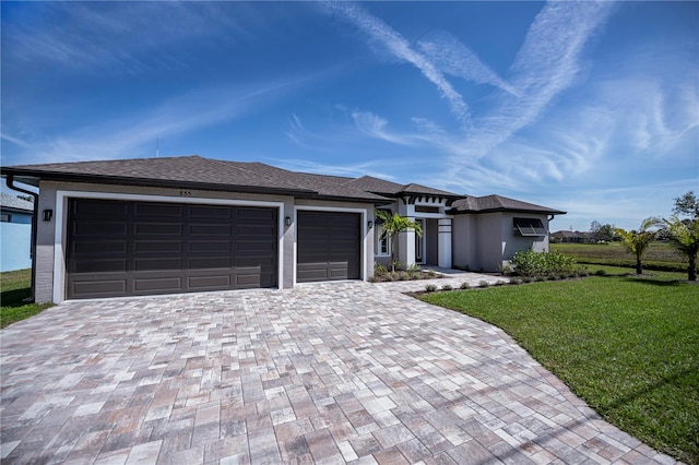 prairie-style house featuring an attached garage, decorative driveway, and a front yard