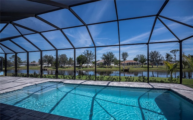 outdoor pool with glass enclosure, a water view, and a patio