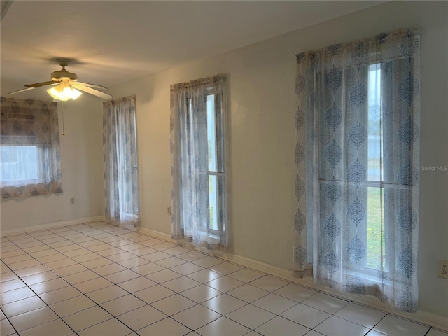 spare room with ceiling fan, baseboards, and light tile patterned floors