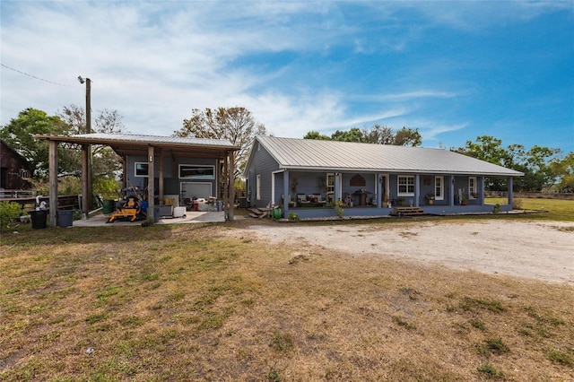 rear view of property featuring a yard, metal roof, and a porch