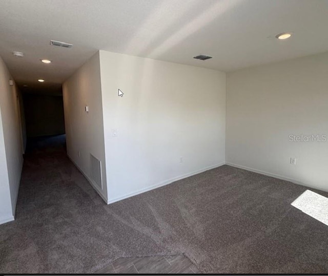 empty room with baseboards, dark carpet, visible vents, and recessed lighting