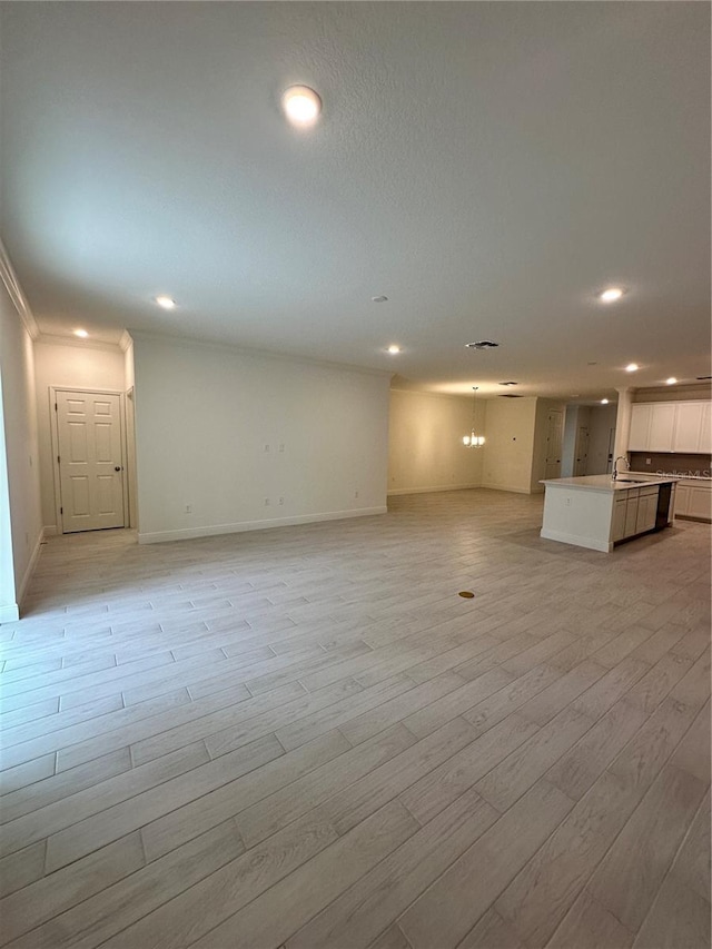 unfurnished living room with light wood-type flooring, a sink, baseboards, and recessed lighting