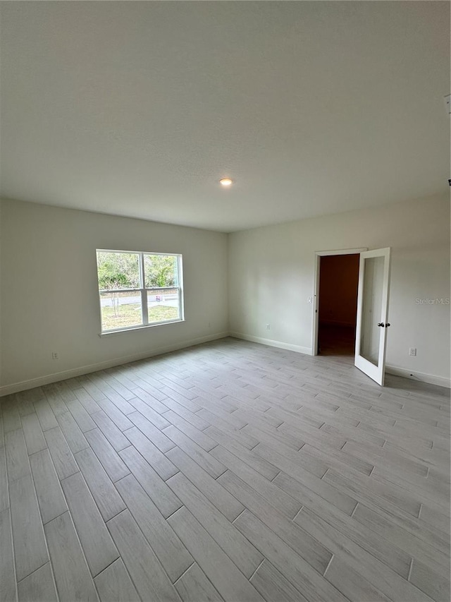 spare room with light wood-type flooring, baseboards, and recessed lighting