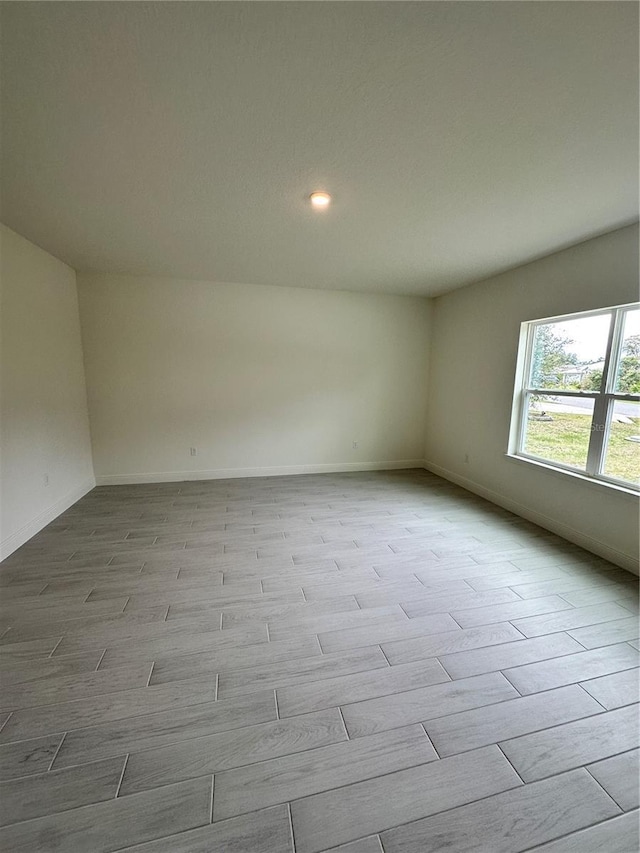 spare room with light wood-style floors and baseboards