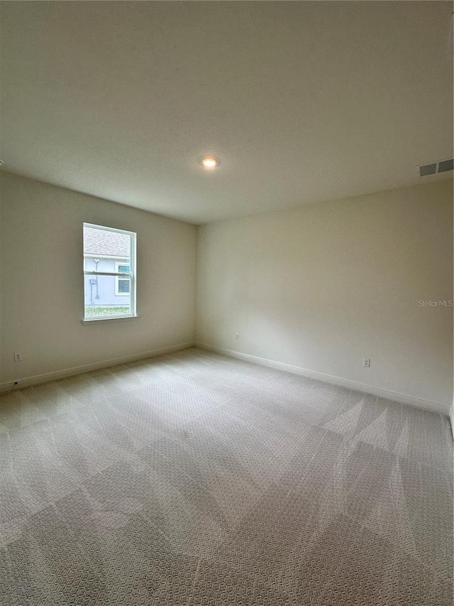 carpeted empty room featuring baseboards, visible vents, and recessed lighting