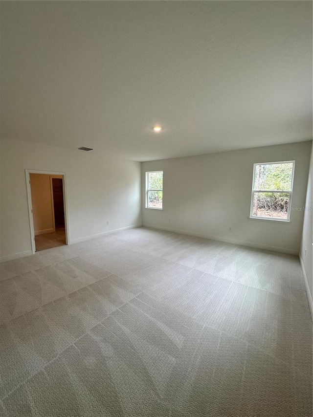 unfurnished room featuring light carpet, baseboards, and visible vents