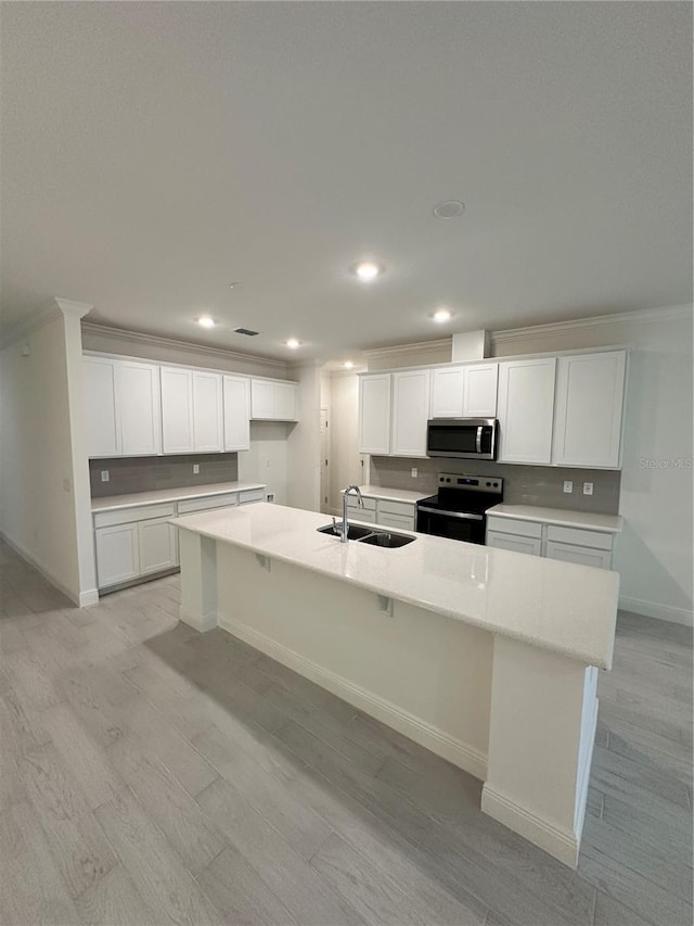 kitchen with an island with sink, electric range, stainless steel microwave, and light countertops