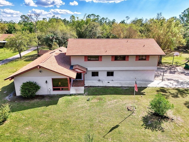 back of property featuring a shingled roof and a lawn