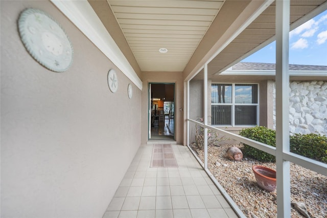 entrance to property featuring stone siding, a shingled roof, and stucco siding