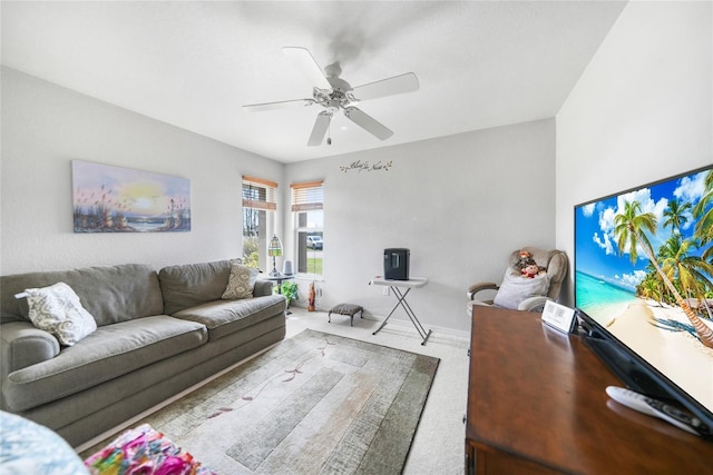 carpeted living area with ceiling fan and baseboards