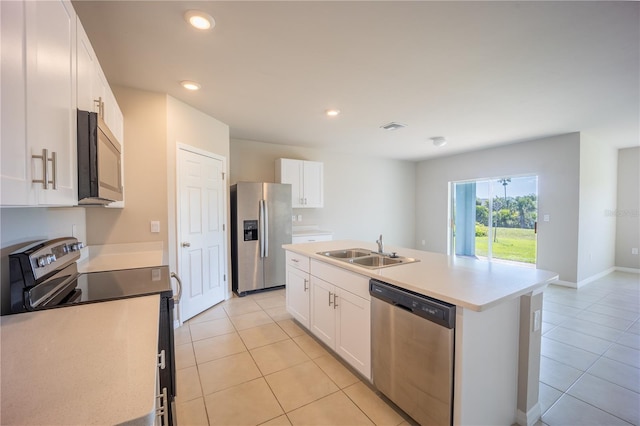 kitchen featuring light tile patterned floors, white cabinets, appliances with stainless steel finishes, and a sink