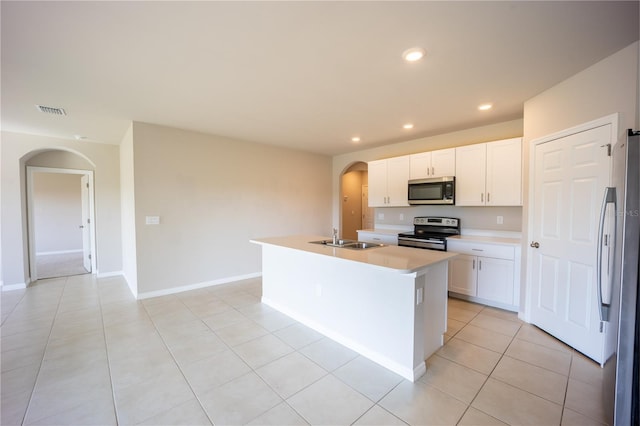 kitchen featuring recessed lighting, arched walkways, a sink, stainless steel appliances, and white cabinetry