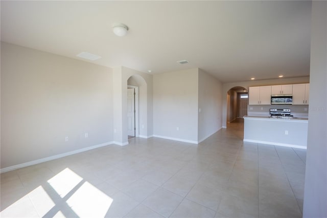 unfurnished living room with visible vents, baseboards, light tile patterned floors, recessed lighting, and arched walkways