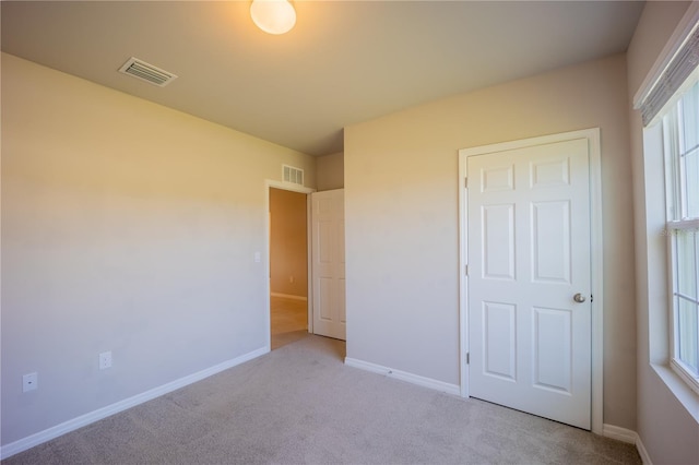 unfurnished bedroom featuring visible vents, baseboards, and light carpet