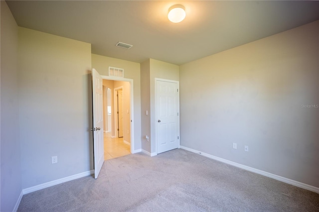 unfurnished bedroom featuring visible vents, light colored carpet, and baseboards