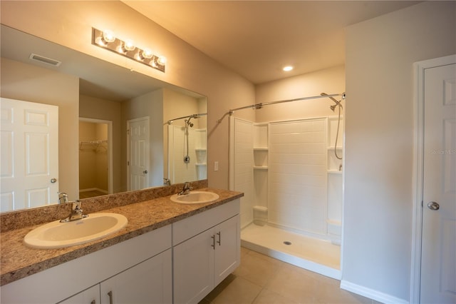 bathroom with tile patterned floors, tiled shower, visible vents, and a sink