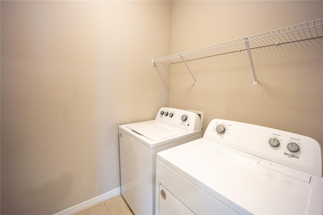 laundry area featuring washer and clothes dryer, laundry area, baseboards, and light tile patterned floors