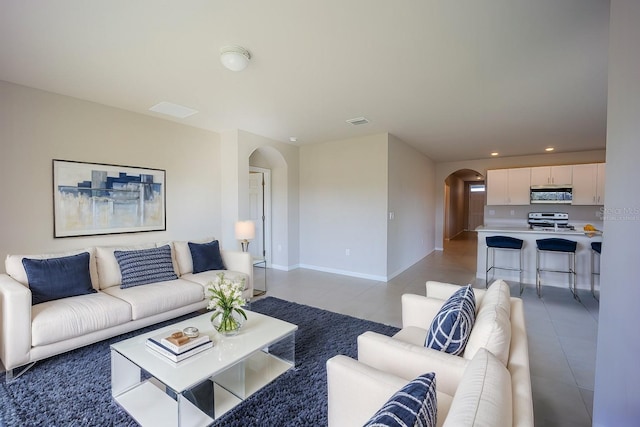 living area with visible vents, baseboards, light tile patterned floors, recessed lighting, and arched walkways