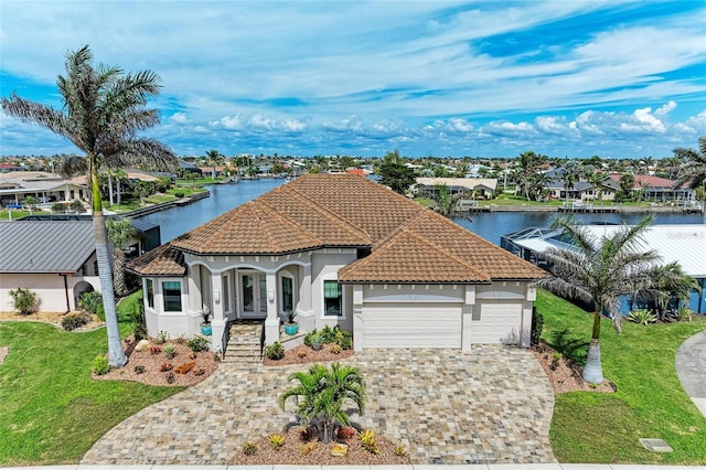 mediterranean / spanish home featuring a front yard, decorative driveway, a tiled roof, and stucco siding