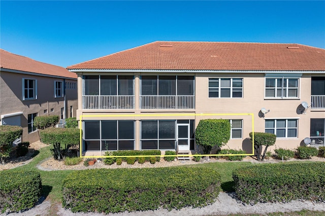 back of property with stucco siding and a tile roof