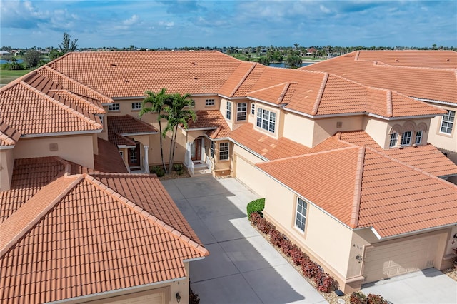 view of front facade with a tiled roof, concrete driveway, and stucco siding