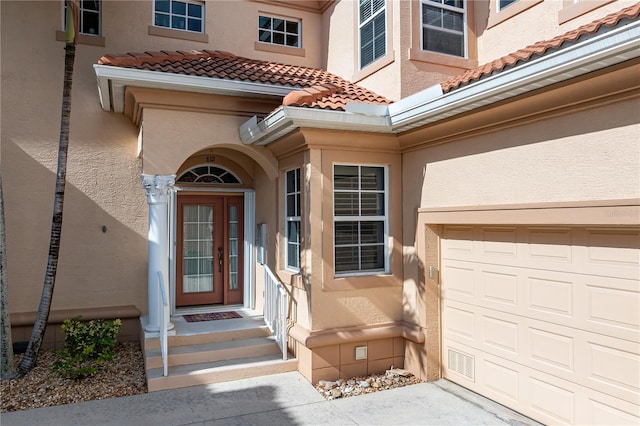 doorway to property featuring stucco siding, a tiled roof, and a garage