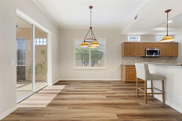 kitchen with visible vents, hanging light fixtures, tasteful backsplash, a kitchen bar, and stainless steel microwave