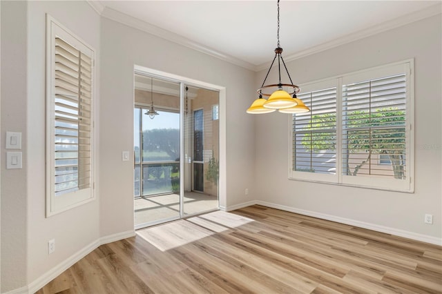 unfurnished dining area featuring ornamental molding, baseboards, a wealth of natural light, and light wood-type flooring