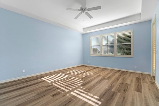 spare room featuring baseboards, a raised ceiling, and wood finished floors