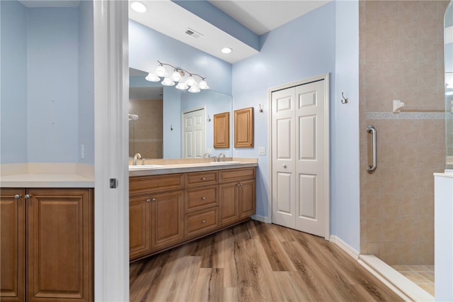 bathroom featuring double vanity, wood finished floors, visible vents, a sink, and a closet