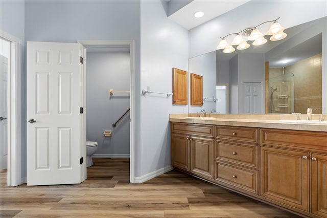 bathroom with a sink, toilet, double vanity, and wood finished floors