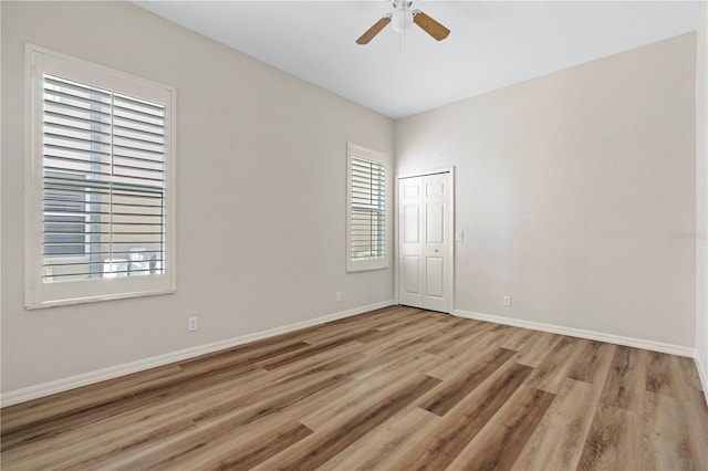 empty room with baseboards, ceiling fan, and light wood finished floors