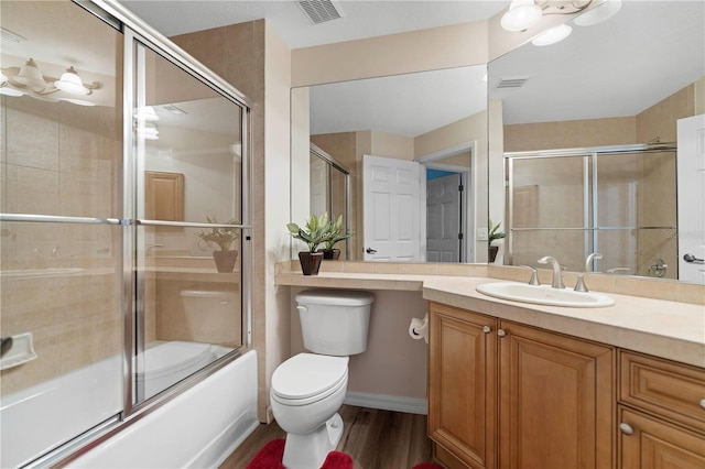 bathroom featuring combined bath / shower with glass door, toilet, vanity, and visible vents