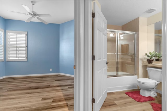 full bath with wood finished floors, visible vents, a ceiling fan, toilet, and enclosed tub / shower combo