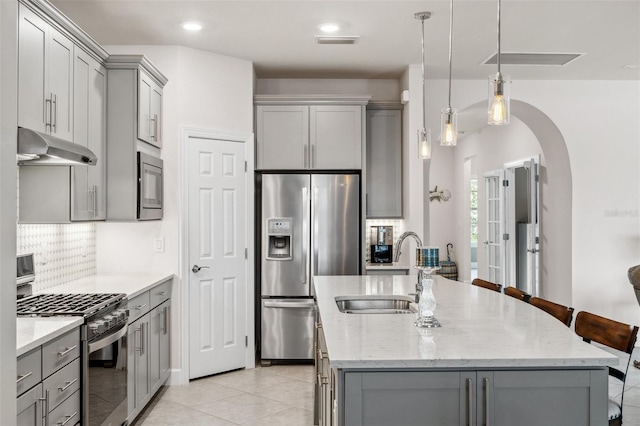 kitchen with a breakfast bar area, appliances with stainless steel finishes, sink, and gray cabinetry